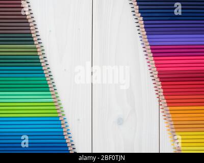 due file di matite colorate su sfondo di legno. vista dall'alto Foto Stock