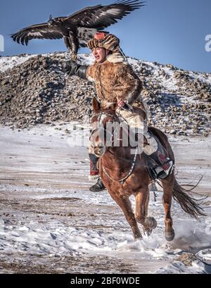 Cacciatore di aquile mongolo, kazako cavalcano con aquila addestrata in inverno, provincia di Bayan-Olgii, Mongolia Foto Stock