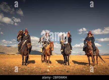 Cacciatori di aquile mongolo, quattro kazaki con aquile addestrate a cavalli nella steppa mongola, provincia di Bayan-Oelgii, Mongolia Foto Stock