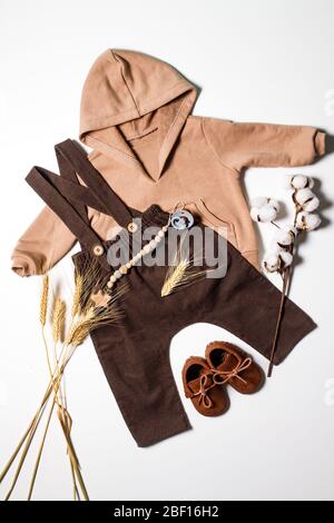 Flatlay di abbigliamento per bambini, scarpe marroni per bambini per l'autunno, pantaloni marroni e felpa con cappuccio beige, vista dall'alto. Foto Stock