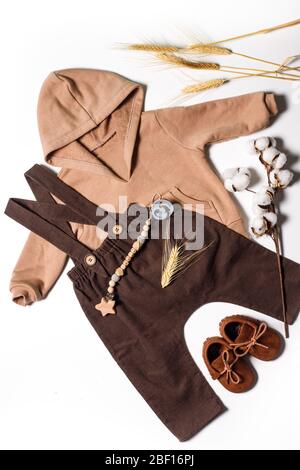 Flatlay di abbigliamento per bambini, scarpe marroni per bambini per l'autunno, pantaloni marroni e felpa con cappuccio beige, vista dall'alto. Foto Stock