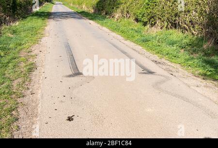 Segni di slittamento pneumatici in gomma nera su una corsia di campagna Foto Stock