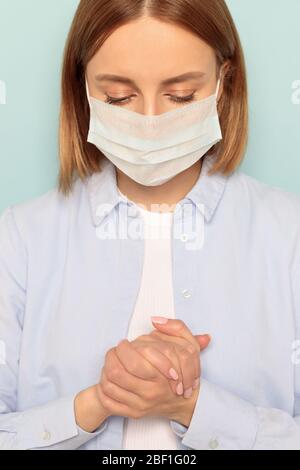 Studio ritratto di donna che indossa una maschera medica viso, pregando con speranza e fede che l'epidemia si concluderà, primo piano, verticale. Protezione contro f Foto Stock