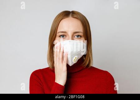 Studio ritratto di donna che indossa una maschera facciale, primo piano, isolato su sfondo grigio. Influenza, allergia alla polvere, protezione contro il virus, coronaviru Foto Stock