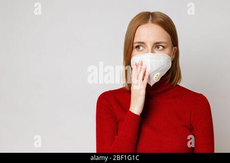 Studio ritratto di donna che indossa una maschera facciale, primo piano, isolato su sfondo grigio. Influenza, allergia alla polvere, protezione contro il virus, coronaviru Foto Stock