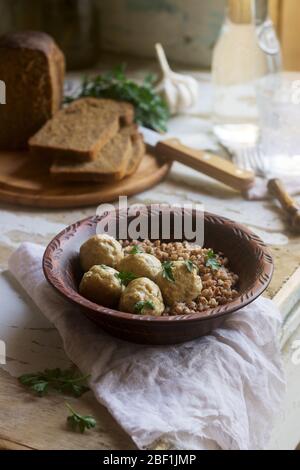 Polpette in salsa di panna acida, servite con porridge di grano saraceno, pane e aglio. Stile rustico. Foto Stock