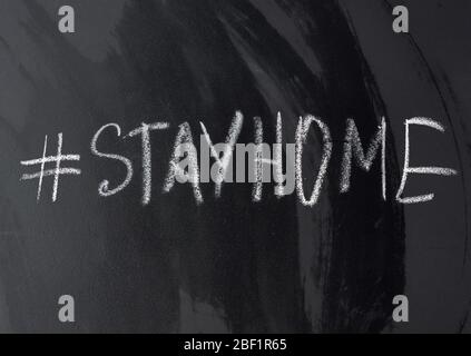iscrizione rimanere a casa in gesso con un hashtag su una lavagna nera, concetto di auto-isolamento in un'epidemia e pandemica Foto Stock