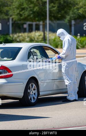 Sugar Land, Texas - 16 aprile 2020: Vestito con completo equipaggiamento protettivo un operatore sanitario raccoglie informazioni da anziani coppia seduta all'interno del loro Foto Stock