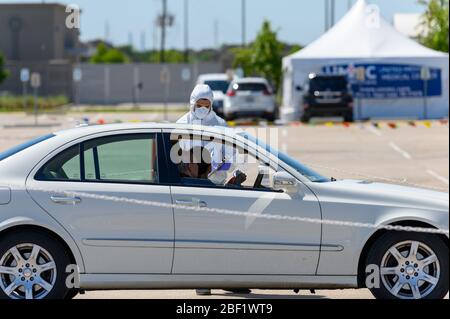 Sugar Land, Texas - 16 aprile 2020: Vestito con completo equipaggiamento protettivo un operatore sanitario raccoglie informazioni da anziani coppia seduta all'interno del loro Foto Stock