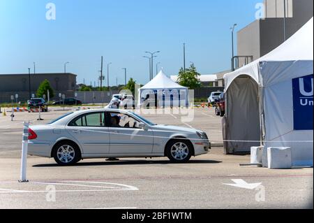 Sugar Land, Texas - 16 aprile 2020: Vestito con completo equipaggiamento protettivo un operatore sanitario raccoglie informazioni da anziani coppia seduta all'interno del loro Foto Stock