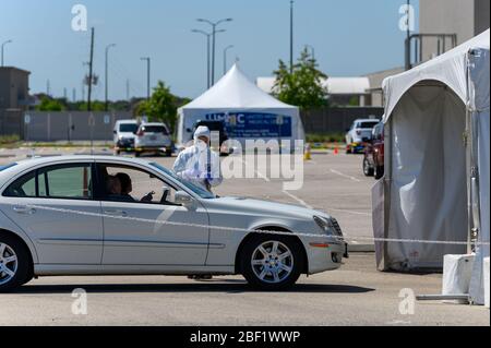 Sugar Land, Texas - 16 aprile 2020: Vestito con completo equipaggiamento protettivo un operatore sanitario raccoglie informazioni da anziani coppia seduta all'interno del loro Foto Stock