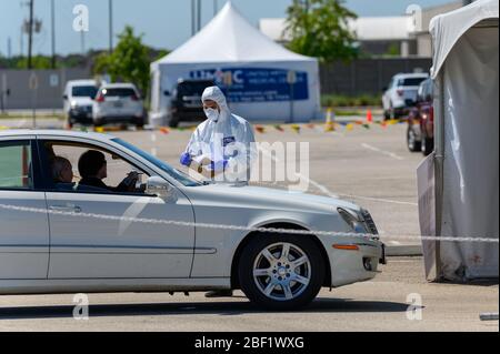 Sugar Land, Texas - 16 aprile 2020: Vestito con completo equipaggiamento protettivo un operatore sanitario raccoglie informazioni da anziani coppia seduta all'interno del loro Foto Stock