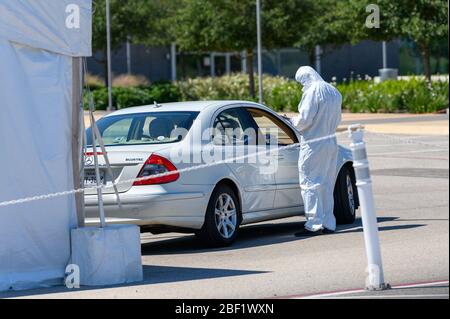 Sugar Land, Texas - 16 aprile 2020: Vestito con completo equipaggiamento protettivo un operatore sanitario raccoglie informazioni da anziani coppia seduta all'interno del loro Foto Stock