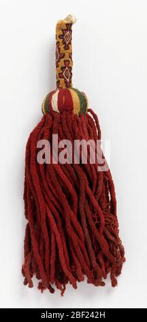Nappina. Grande nappina con lunghe frange di lana rossa ritorte e filo di lana stirate in 1/4' di banda bianca, rossa, verde, gialla sulla parte superiore del nucleo, e un grosso stelo rigido di fili di cotone avvolto strettamente con fili di cotone su cui sembra essere il punto di gambo Foto Stock