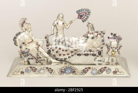 Gruppo scultoreo. Cast argento, gioiello incrostato tavolo mostrando soldato romano in piena regalia seduta di fronte alla donna egiziana reclinato sul divano, e foned da servo in piedi; piccolo tavolo a treppiede a destra del divano, tenendo ciotola di frutta o fiori e urna sullo scaffale sotto. Foto Stock