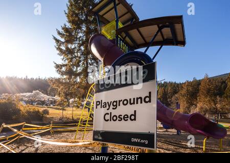 NORTH VANCOUVER, BC, CANADA - Apr 11, 2020: Un parco giochi chiuso in un parco pubblico North Vancouver fiancheggiato da nastro di attenzione per aiutare a limitare il Foto Stock