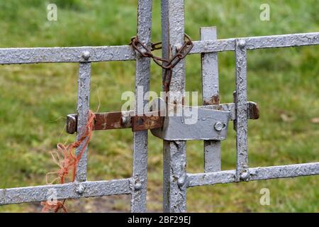 Cancelli di vecchia fattoria di metallo fissati da traversa-barra e corda di nylon arancione all'ingresso al campo. Foto Stock