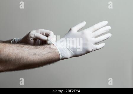 Un primo piano di un mans mani che indossano guanti in lattice. Foto Stock