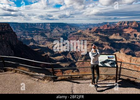 GRAND CANYON, ARIZONA - 6 NOVEMBRE 2017: Giovane donna in piedi sul bordo del Grand Canyon facendo una fotografia. Donna escursionista del Grand Canyon che riposa Foto Stock