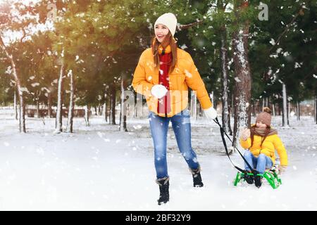 Madre con bambina in slitta nel parco il giorno d'inverno Foto Stock