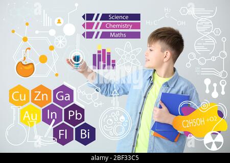 Carino scolaretto con vetreria da laboratorio e disegni su sfondo grigio Foto Stock