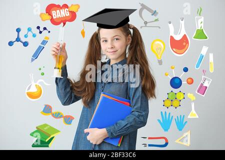 Carina piccola scolaretta con vetreria da laboratorio su sfondo grigio Foto Stock