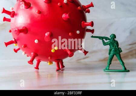 Gli uomini dell'esercito del giocattolo verde attaccano e combattono fuori del coronavirus come metafora per il sistema immune umano Foto Stock