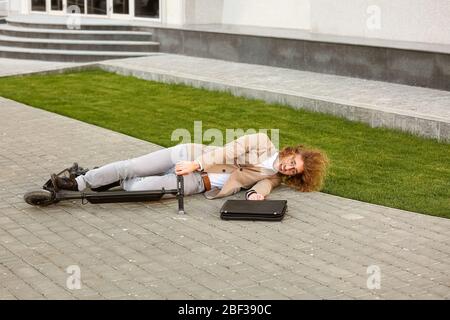 Giovane uomo caduto fuori dal suo scooter da calcio all'aperto Foto Stock