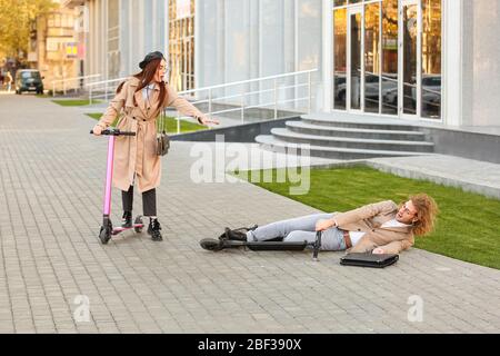 Giovane uomo caduto fuori dal suo scooter da calcio all'aperto Foto Stock