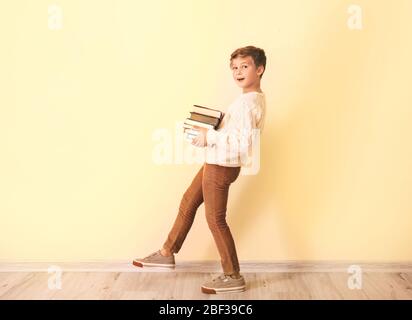 Ragazzino con libri vicino alla parete a colori Foto Stock