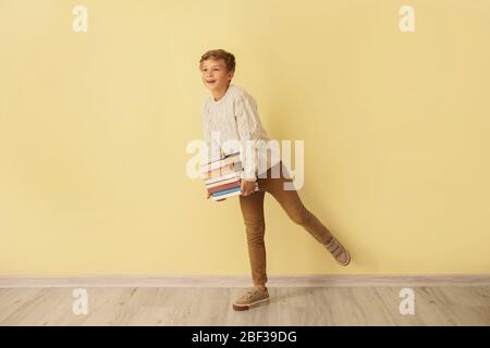 Ragazzino con libri vicino alla parete a colori Foto Stock