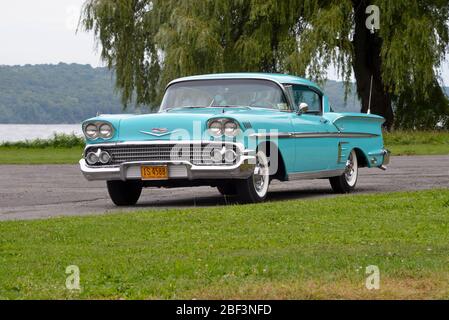 Turquoise 1958 Chevrolet Impala coupé tre quarti di vista frontale contro salice albero al lago Foto Stock