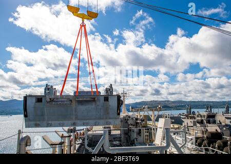 BASE NAVALE GUAM (15 aprile 2020) marinai della marina statunitense assegnati al battaglione per la movimentazione del carico della marina (NCHB) 1, Mantenere la tensione sulle linee poiché un modulo spiaggia del sistema di illuminazione navale (INLS) migliorato viene sollevato da una gru durante un'operazione per scaricare le apparecchiature per la costruzione di un impianto medico di spedizione (EMF) dalla nave da carico di veicoli della classe Watson USNS Dahl (T-AKR-312). L’EMF fornirà maggiori capacità mediche a sostegno della risposta del DOD COVID-19 e consentirà alle forze di essere obbligate a sostenere Guam e la regione se viene richiesta una missione di sostegno alla difesa delle autorità civili. (STATI UNITI Navy ph Foto Stock