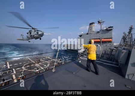 OCEANO PACIFICO (10 aprile 2020) il Mate di Boatswain della U.S. Navy Eric Alexander di seconda classe, di Houston, guida un falco marino MH-60R, assegnato ai "Scorpioni" dell'elicottero Maritime Strike Squadron (HSM) 49, al ponte di volo del cacciatorpediniere guidato Arleigh Burke-class USS Rafael Peralta (DDG 115) per lasciare le forniture durante un rifornimento in mare. Il "Scorpions" di elicottero Maritime Strike Squadron (HSM) 49 è schierato, con il cacciatorpediniere guidato Arleigh Burke-classe USS Rafael Peralta (DDG 115), nella settima flotta degli Stati Uniti di operazioni a sostegno della sicurezza e della stabilità nel Foto Stock