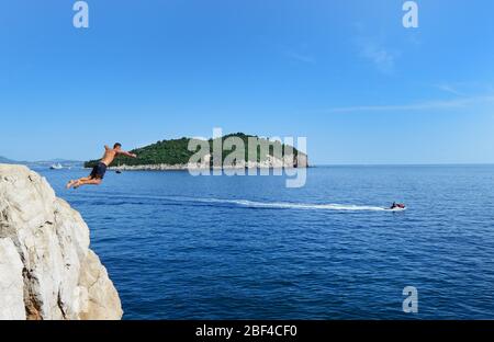 Il salto - saltando nel mare Adriatico dalle scogliere sotto le mura della città vecchia di Dubrovnik, Croazia. Foto Stock