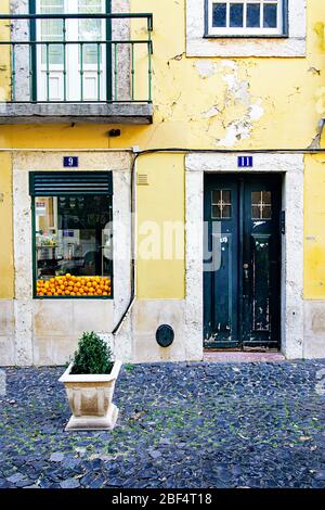 Le arance si accumulano nella finestra di un caffè in un edificio giallo nel quartiere di Alfama a Lisbona, Portogallo Foto Stock