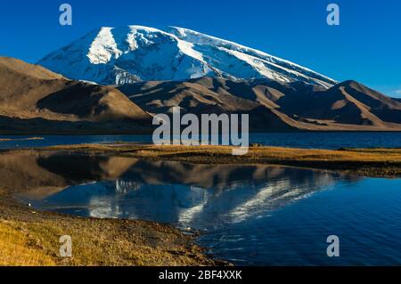 Picco Muztagata riflessa nelle acque cristalline del Lago Karakul, provincia dello Xinjiang Cina Foto Stock