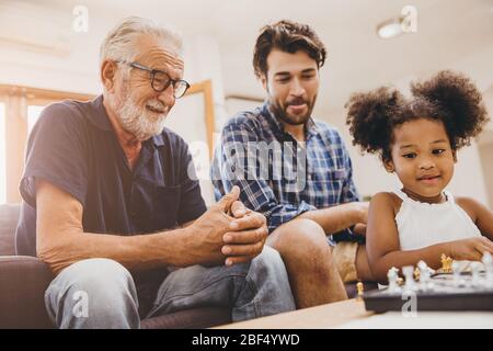 Felice famiglia momento anziano con bambino bambina e figlio a casa felicità momento giocando a scacchi gioco. Foto Stock