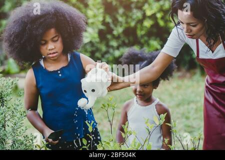 Famiglia bella giardinaggio annaffiatura verde attività vegetale con i bambini durante il soggiorno a casa per ridurre lo scoppio del Coronavirus. Bambini che annaffia t Foto Stock
