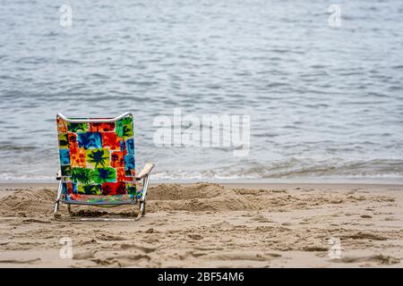 sedia colorata solitaria sulla spiaggia vicino all'oceano, concetto di vacanza estiva con spazio per le copie Foto Stock