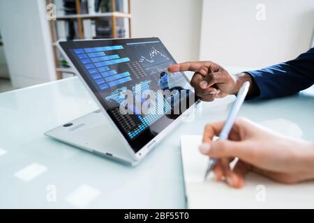 Due imprenditori che lavorano insieme con grafico finanziario su Laptop Foto Stock