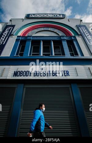 Un uomo cammina oltre O2 Academy, Glasgow, indossando maschera facciale con il segno sopra che dice: 'NHS - nessuno lo fa meglio. Foto Stock