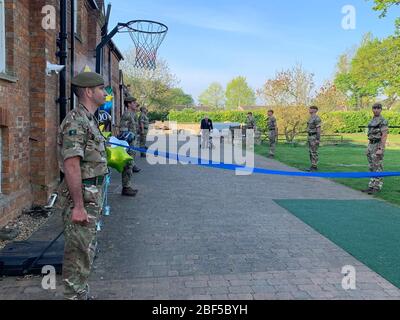 (200417) -- LONDRA, 17 aprile 2020 (Xinhua) -- Tom Moore(C), un funzionario in pensione e veterano della seconda guerra mondiale, cammina il suo ultimo giro al suo giardino come soldati del reggimento dello Yorkshire si levano da parte a Bedfordshire, Gran Bretagna, il 16 aprile 2020. Il veterano di guerra di 99 anni ha raccolto più di 12 milioni di sterline (15 milioni di dollari USA) per il Servizio sanitario Nazionale (NHS) completando 100 giri del suo giardino. Con l'aiuto di un telaio di camminata, Tom Moore, un funzionario in pensione e veterano della seconda guerra mondiale, aveva progettato fare 100 giri del suo giardino nel Bedfordshire, Inghilterra, prima del suo 100esimo Foto Stock