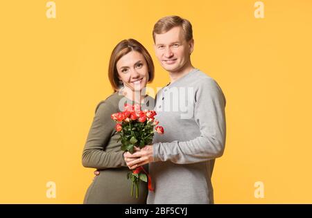 Ritratto di bella coppia con bouquet di fiori su sfondo colorato Foto Stock