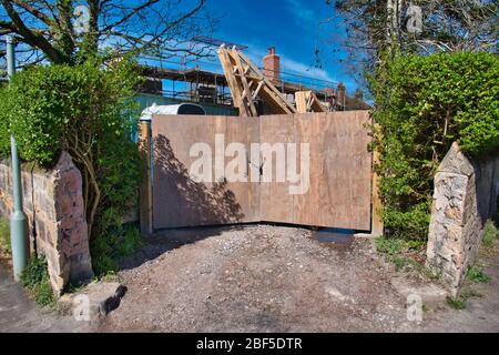 In una giornata di sole, le porte di legno in un edificio casa / cantiere sono chiusi e chiusi durante il governo britannico coronavirus blocco Foto Stock