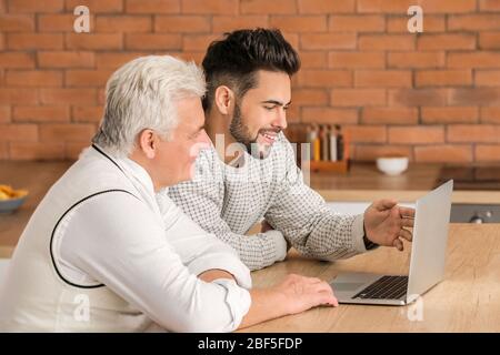 Giovane e padre con computer portatile in cucina Foto Stock