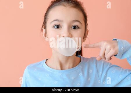 Ragazza carina con chewing gum su sfondo a colori Foto Stock