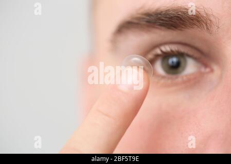 Giovane uomo che mette in lenti a contatto, closeup Foto Stock