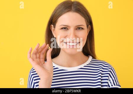 Giovane donna con olio di pesce su sfondo colorato Foto Stock