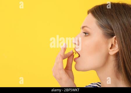 Giovane donna con olio di pesce su sfondo colorato Foto Stock